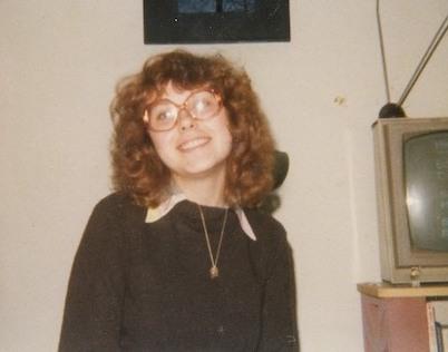 20-something Jacky Rosen with big 70s glasses and curly red hair in her dorm