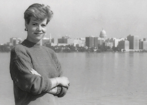 Tammy Baldwin in her twenties posing in front of a skyline