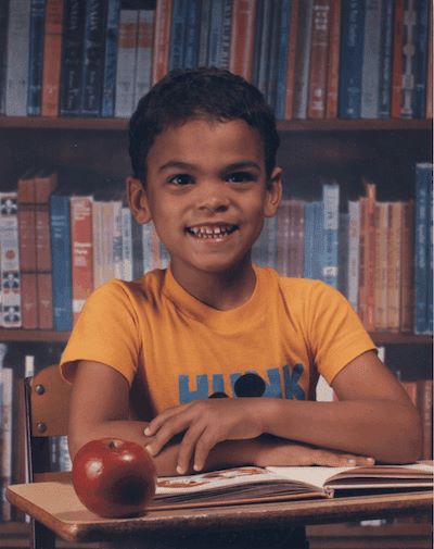 Colin Allred as a child in front of a bookshelf.